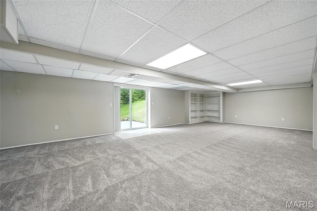 carpeted empty room with baseboards and a drop ceiling