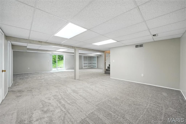 below grade area featuring stairway, a drop ceiling, carpet flooring, and baseboards
