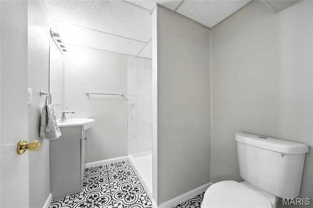 full bathroom with toilet, baseboards, a shower stall, vanity, and a paneled ceiling