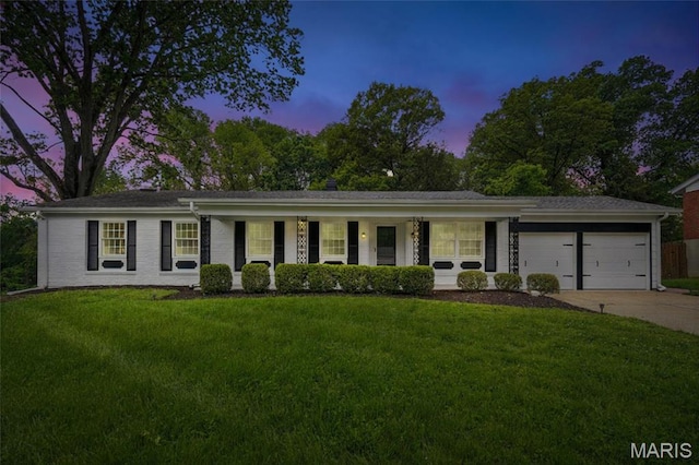 ranch-style home featuring an attached garage, concrete driveway, a front yard, and covered porch