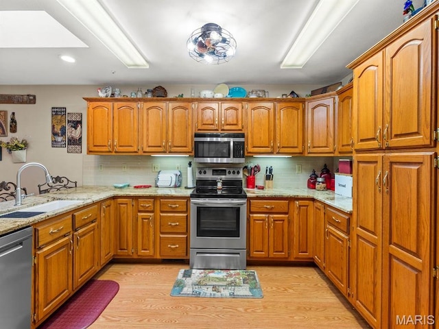 2700 Woods Way, Belleville, IL 62221 - kitchen featuring appliances with stainless steel finishes, a sink, brown cabinetry, light stone countertops, and backsplash