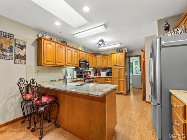 2700 Woods Way, Belleville, IL 62221 - kitchen featuring stainless steel appliances, a sink, a peninsula, light wood-type flooring, and brown cabinets