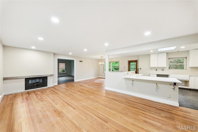 18 Spoede Hills Dr, Saint Louis, MO 63141 - unfurnished living room with a chandelier, recessed lighting, a multi sided fireplace, baseboards, and light wood-type flooring