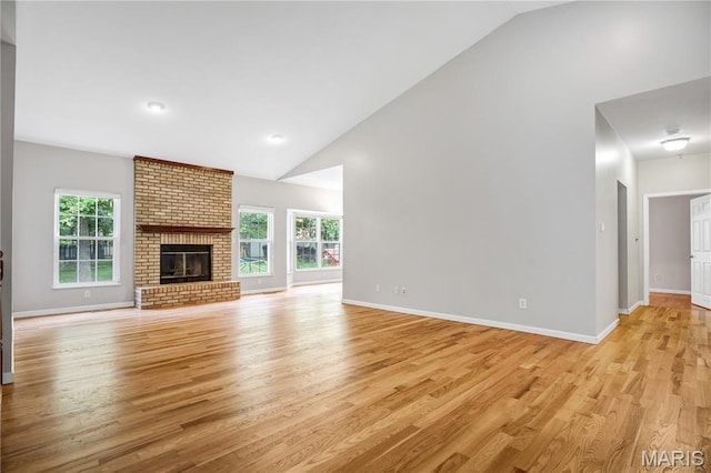 1587 Paradise Valley Dr, High Ridge, MO 63049 - unfurnished living room with healthy amount of natural light, light wood-style floors, high vaulted ceiling, and a brick fireplace