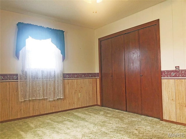 603 W Bloomfield Ave, Bloomfield, MO 63825 - unfurnished bedroom featuring carpet, wainscoting, a closet, and wooden walls