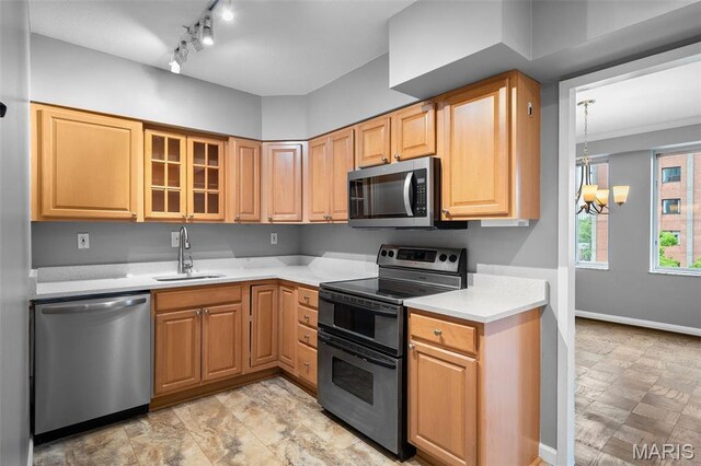 900 S Hanley Rd Unit 7B, Saint Louis, MO 63105 - kitchen featuring appliances with stainless steel finishes, a sink, light countertops, a chandelier, and glass insert cabinets