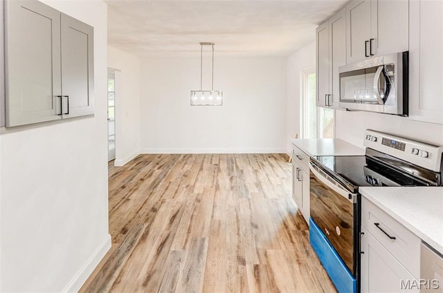 14 Carson Dr, Belleville, IL 62223 - kitchen featuring appliances with stainless steel finishes, light wood-style flooring, light countertops, a chandelier, and baseboards