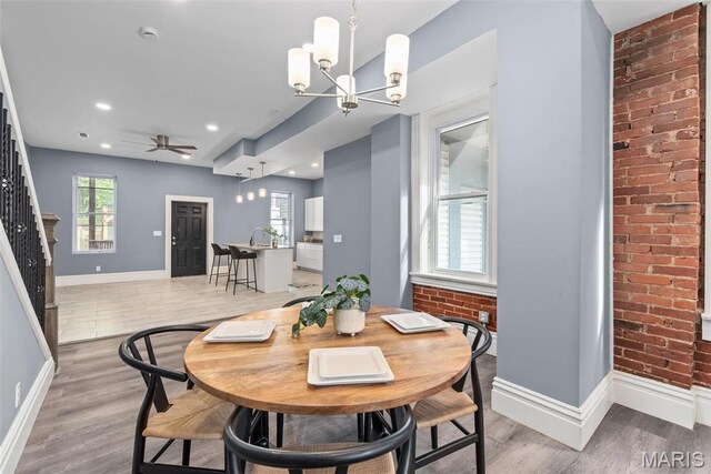 3244 Michigan Ave, Saint Louis, MO 63118 - dining space featuring a chandelier, baseboards, light wood-style flooring, brick wall, and recessed lighting