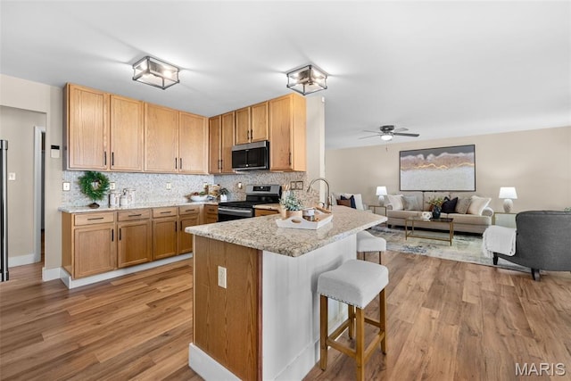 2222 Harborside Dr, Ofallon, MO 63368 - kitchen featuring stainless steel appliances, light wood-type flooring, a peninsula, a kitchen breakfast bar, and ceiling fan