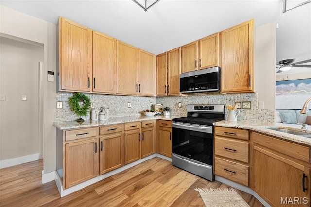 2222 Harborside Dr, Ofallon, MO 63368 - kitchen with stainless steel appliances, a sink, light wood-style flooring, tasteful backsplash, and baseboards