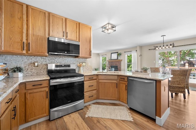 2222 Harborside Dr, Ofallon, MO 63368 - kitchen with appliances with stainless steel finishes, a peninsula, light wood-style flooring, and a sink