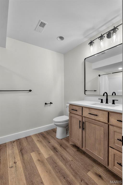 242 Orange Bowl Dr, Cape Girardeau, MO 63701 - bathroom featuring wood finished floors, toilet, vanity, and baseboards