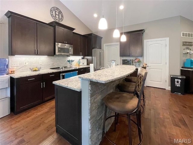 9794 Cedar Dr, Hillsboro, MO 63050 - kitchen with appliances with stainless steel finishes, a kitchen breakfast bar, tasteful backsplash, light stone counters, and dark wood-style floors