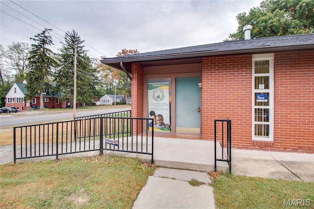 entrance to property featuring brick siding and covered porch