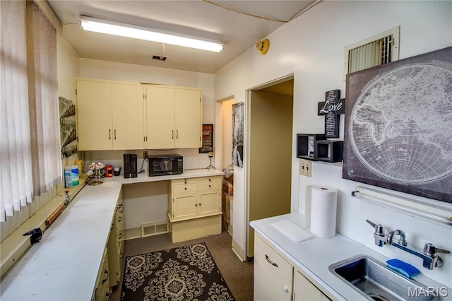 kitchen featuring a sink, light countertops, cream cabinets, and black microwave