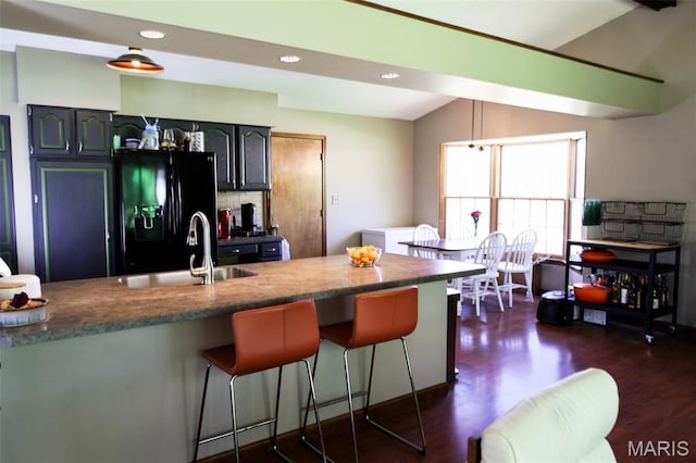 5501 Dober Ln, Saint Louis, MO 63129 - kitchen featuring black fridge with ice dispenser, a sink, a breakfast bar, dark wood-style floors, and vaulted ceiling