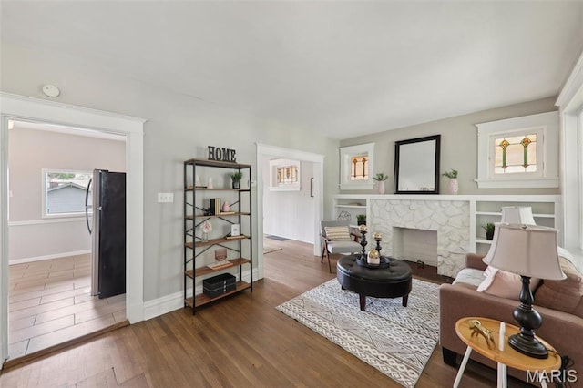 4942 Bonita Ave, Saint Louis, MO 63109 - living room with wood finished floors, a stone fireplace, and baseboards