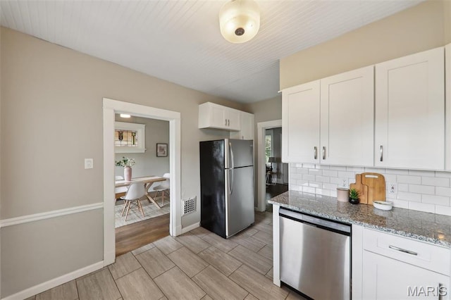 4942 Bonita Ave, Saint Louis, MO 63109 - kitchen with stainless steel appliances, tasteful backsplash, white cabinetry, stone counters, and baseboards