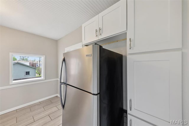 4942 Bonita Ave, Saint Louis, MO 63109 - kitchen with freestanding refrigerator, white cabinetry, light wood-type flooring, and baseboards