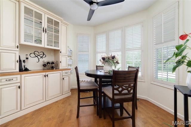 dining area featuring light wood-style floors, a ceiling fan, and baseboards