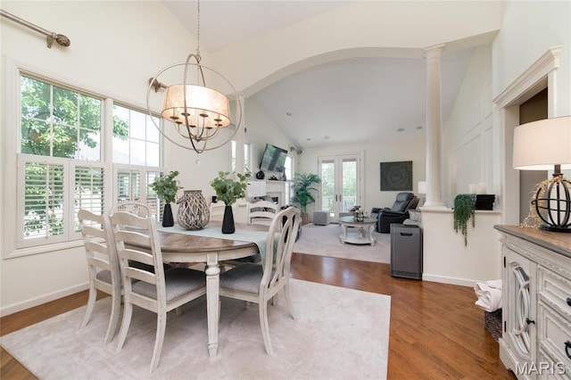 dining space with lofted ceiling, a chandelier, dark wood-style flooring, ornate columns, and arched walkways