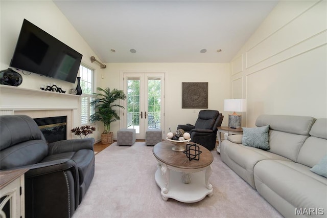 living room with lofted ceiling, a glass covered fireplace, carpet floors, and french doors