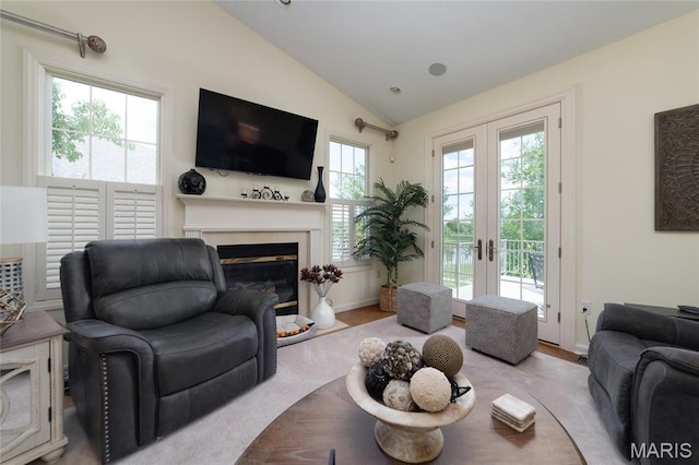 living area featuring vaulted ceiling, a glass covered fireplace, french doors, and wood finished floors