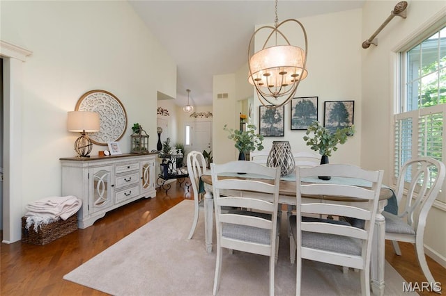 dining room with high vaulted ceiling, a chandelier, and wood finished floors