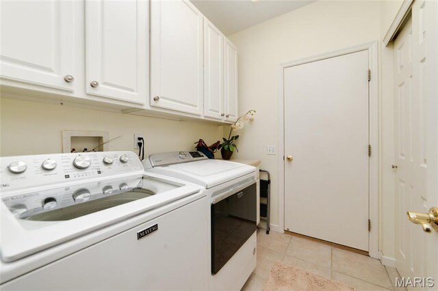 clothes washing area with cabinet space, washing machine and clothes dryer, light tile patterned flooring, and baseboards