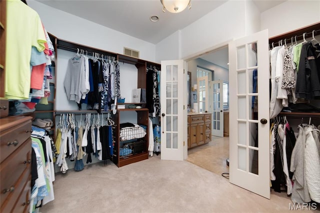 spacious closet with french doors and light carpet