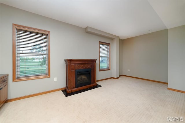 unfurnished living room featuring light carpet, baseboards, and a fireplace with flush hearth