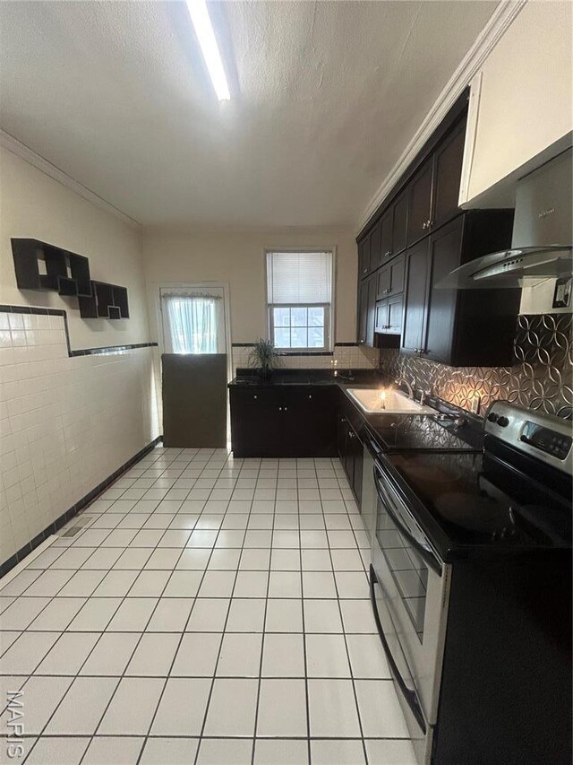 719 Leland Ave, Saint Louis, MO 63130 - kitchen featuring stainless steel electric stove, dark countertops, a sink, wall chimney range hood, and backsplash