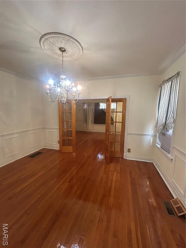 719 Leland Ave, Saint Louis, MO 63130 - unfurnished dining area featuring a chandelier, a decorative wall, hardwood / wood-style flooring, crown molding, and wainscoting
