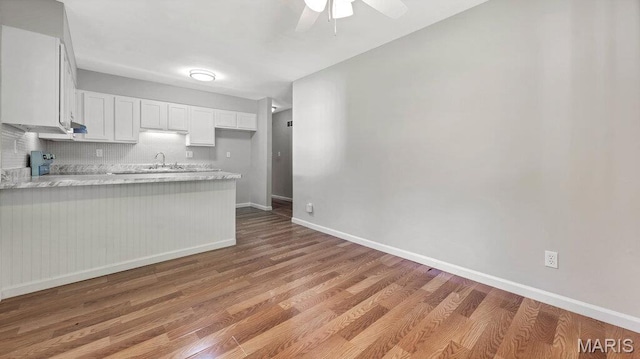 939 Vosholl Ave, Warrenton, MO 63383 - kitchen featuring a peninsula, baseboards, white cabinets, and light wood-type flooring