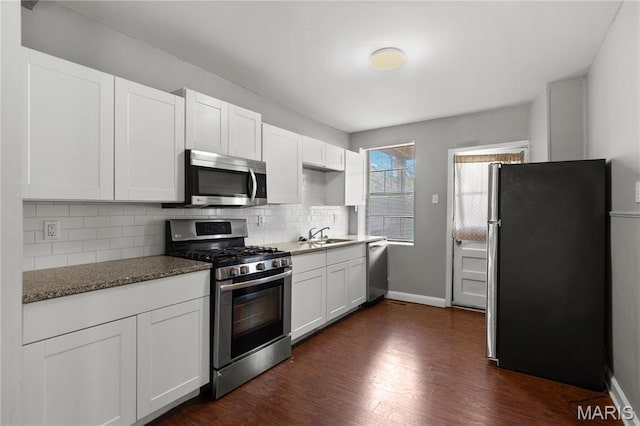 1016 Tamm Ave, Saint Louis, MO 63139 - kitchen featuring stainless steel appliances, decorative backsplash, white cabinetry, dark wood finished floors, and a sink
