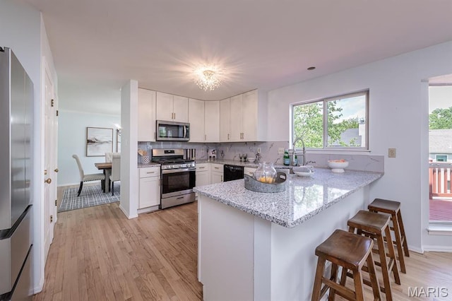 200 Kylewood Ct, Ballwin, MO 63021 - kitchen with appliances with stainless steel finishes, a sink, a peninsula, and white cabinetry