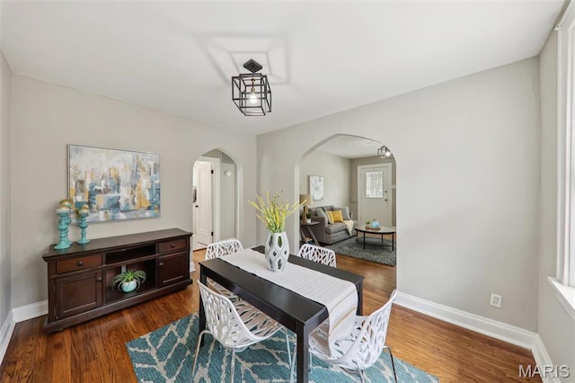 5909 Hampton Ave, Saint Louis, MO 63109 - dining room featuring arched walkways, dark wood-style floors, and baseboards