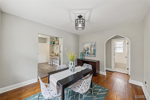 5909 Hampton Ave, Saint Louis, MO 63109 - dining room featuring arched walkways, baseboards, and dark wood-type flooring