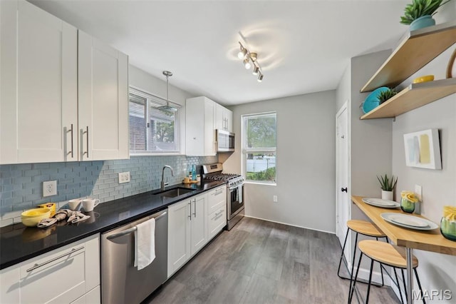 5909 Hampton Ave, Saint Louis, MO 63109 - kitchen featuring stainless steel appliances, a sink, dark countertops, white cabinets, and tasteful backsplash