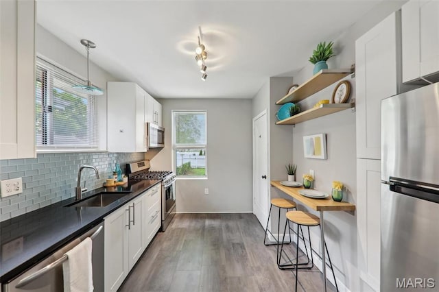 5909 Hampton Ave, Saint Louis, MO 63109 - kitchen featuring stainless steel appliances, a sink, dark countertops, open shelves, and tasteful backsplash