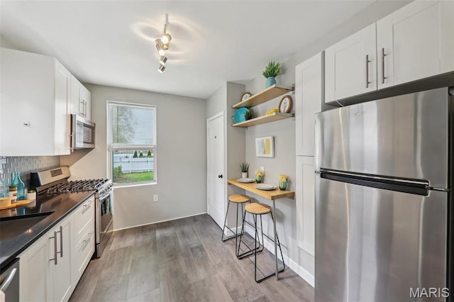 5909 Hampton Ave, Saint Louis, MO 63109 - kitchen featuring appliances with stainless steel finishes, open shelves, decorative backsplash, white cabinets, and dark countertops