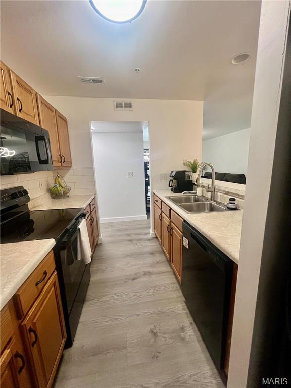 3605 Tracey Rich Rd Unit 1A, Saint Louis, MO 63125 - kitchen with black appliances, a sink, light countertops, brown cabinets, and decorative backsplash