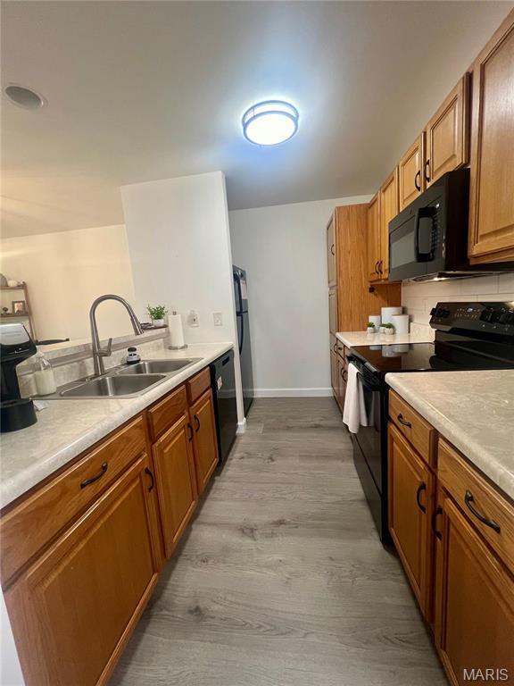 3605 Tracey Rich Rd Unit 1A, Saint Louis, MO 63125 - kitchen with black appliances, a sink, light wood-type flooring, baseboards, and light countertops