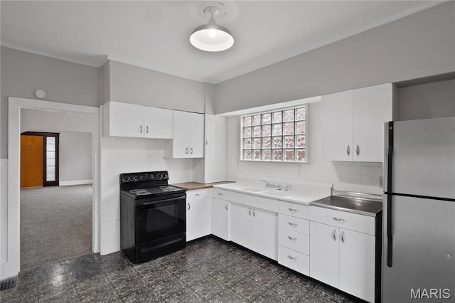 kitchen featuring freestanding refrigerator, black electric range, a sink, white cabinets, and dark flooring