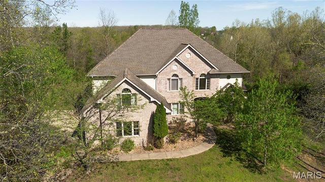 view of front of home with roof with shingles and brick siding