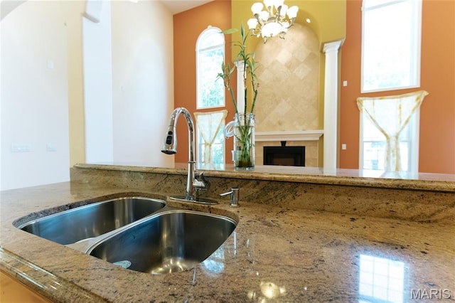 1025 Cobblestone Dr, Rolla, MO 65401 - detailed view of a sink, stone countertops, a tile fireplace, and a chandelier