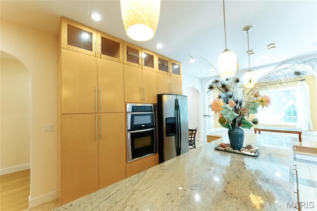 1025 Cobblestone Dr, Rolla, MO 65401 - kitchen featuring arched walkways, stainless steel appliances, light stone countertops, recessed lighting, and glass insert cabinets