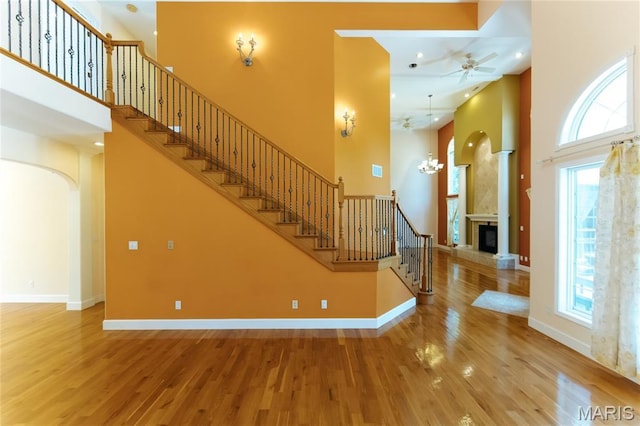 1025 Cobblestone Dr, Rolla, MO 65401 - stairs featuring a towering ceiling, a high end fireplace, wood finished floors, arched walkways, and ceiling fan