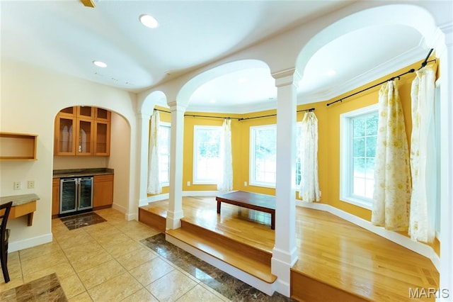 1025 Cobblestone Dr, Rolla, MO 65401 - unfurnished living room featuring wine cooler, decorative columns, plenty of natural light, ornamental molding, and recessed lighting