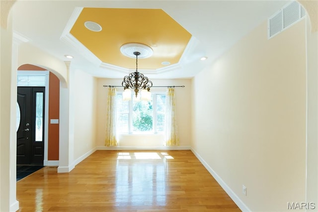 1025 Cobblestone Dr, Rolla, MO 65401 - unfurnished dining area featuring a raised ceiling, a chandelier, light wood-style floors, arched walkways, and crown molding